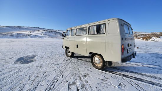 Weisser Van bei Schnee unter strahlend blauem Himmel.