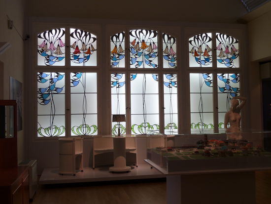 Repräsentativer Raum mit Jugendstilfenstern und zahlreichen Exponaten - Möbel, Gebrauchsgegenstände und Gemälde