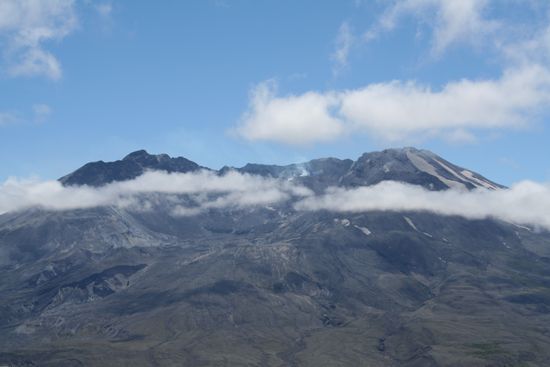 Der neue Dom im Krater des Mount St. Helens. Etwas rechts von der Mitte zwischen den beiden Wolkenstreifen sieht man blauen Rauch aufsteigen