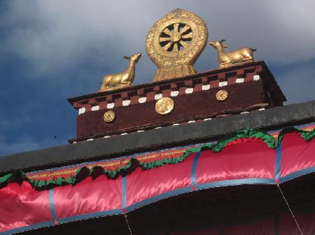 Das Dharma Rad auf dem Dach des Jokhang. Das Rad symbolisiert Dharma - die Lehre Buddhas, welche unter anderem beschreibt, wie man sich aus dem ewigen Kreislauf von Geburt, Tod und Wiedergeburt befreien kann. Wer das Dharma-Rad tr&auml;gt, soll nach buddhistischem Glauben Gl&uuml;ck, absoluten Frieden und innere Perfektion finden.