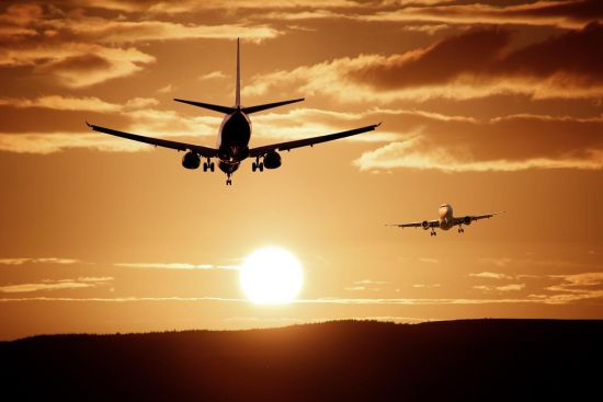 Bild zweier landender Flugzeuge mit untergehender Sonne.