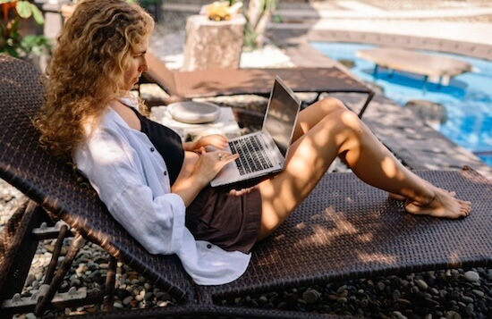 Bild einer Reisenden mit ihrem Notebook entspannt am Pool.