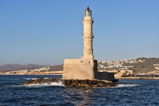 Leuchtturm von Chania auf Kreta im klaren Herbstlicht mit ruhiger See und Altstadt im Hintergrund.