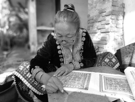 Eine Hmong-Frau markiert den Stoff zur Vorbereitung der Indigofärbung.