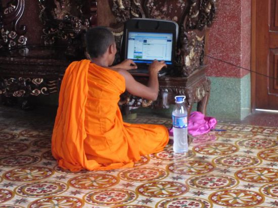 Und dieses Bild gefaellt uns besonders: Ein Moench, der auf dem Boden der Tempelhalle im Internet surft - Fortschritt laesst sich eben nicht aufhalten 