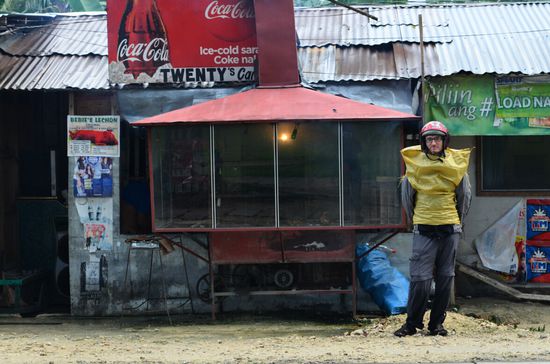 Mangels käuflich zu erwerbender Pelerine musste ich diese Alternative wählen - ein Sack, der normalerweise Schweinefutter beinhaltet - für den musste ich auch noch 8 Pesos auf den Tisch legen und dazu hat es unterm Arm ein wenig gezwickt.
C: Da stand er dort im Schweinefuttersack &amp; wartete auf sein Grillhaehnchen 