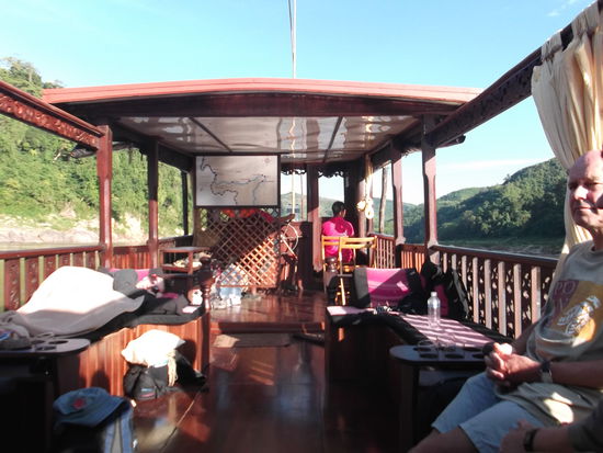 Das Sonnendeck! 
Und wer Lust auf ein Sonnenbad hatte, konnte es sich auf dem Dach bequem machen. Begreiflicherweise hatte niemand von diesem Angebot gebrauch gemacht. Denn es war ziemlich luftig da oben und der Sonnenbrand hätte nicht lange auf sich warten lassen. 
Uta kommt aus Kiel, ist schon ein Monat unterwegs und wird noch 5 weitere Monate durch Südostasien reisen. Sie geniesst es, den Winter in angenehmerem Klima verbringen zu können. Wir hatten schnell einen guten Draht zueinander gefunden und beschlossen, die Tage in Luang Prabang gemeinsam in einem Guesthaus  zu verbringen,  um damit etwas Geld zu sparen. Denn hier bezahlt man als Alleinreisende immer für ein 2-er Zimmer. Somit können wir unsere Kosten teilen. Vorerst genossen wir aber unsere Fahrt auf der Shompoo Cruise, wo uns der Kellner "Kam" mit Flüssiger und fester Nahrung versorgte. Er war sehr aufmerksam und fragte immer wieder nach unseren Wünschen.  Schon bald war Zeit fürs Mittagessen. Kam servierte uns eine feine Suppe mit Seegras aus dem Mekong, das schmeckte und auch aussah wie Spinat. Ich würzte die Suppe nur leicht nach. Kurz darauf brach aber sehr schnell ein Brand aus in meinem Mund, weil ich wahrscheinlich zuviel Chili erwischt hatte. Macht nichts, ich war zwar nicht in der Feuerwehr, aber ich weiss trotzdem, dass man Brände mit Wasser löschen kann. Das hat auch geholfen. Nun war ich bereit für die Hauptspeise. Kam servierte ein feines Süss-saures Chicken Gericht mit Reis und in Bananenblättern gebratenem Fisch. Auf den Fisch habe ich, zugunsten meiner Mitesser, grosszügig verzichtet. Als Dessert tischte Kam uns einen Früchte Koktail aus Mango und Dragon-Fruit auf. Das war aber  sehr lecker. Ich weiss, ich brauche schon deutsche und englische Wörter in meinem Wortschatz. Ihr glaubt sicher, es wird Zeit , dass ich bald wieder nach Hause komme. Aber darauf müsst ihr noch eine Woche warten. 
Nach dem feinen Essen waren alle ziemlich müde. Es war Zeit für die Siesta.