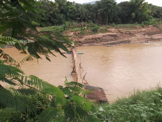 Ich schnappte mir also das Bike und machte mich auf den Weg, alles dem Wasser entlang.
Zuerst fuhr ich dem Mekong entlang, bis zum Spitz der Halbinsel. Dann ging es dem Seitenfluss entlang in Richtung Niemandsland. Diese Fussgängerbrücke ist immer noch in Luang Prabang. Daran wurde gerade noch etwas geflickt und war mit dem Bike nicht passierbar.