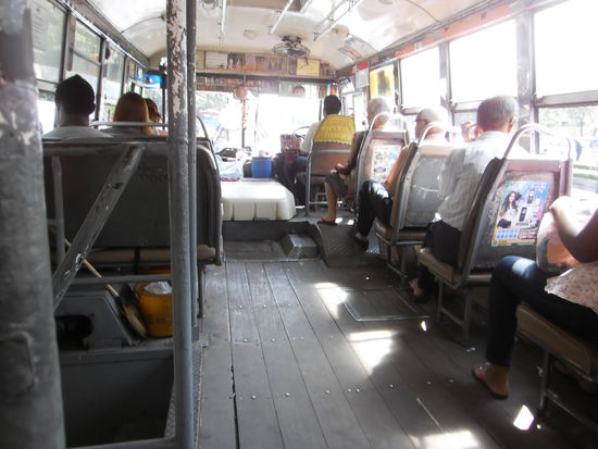 und so sehen sie von Innen aus. Ein Bretterboden und links und rechts gepolsterte Sitze. Sie sind sogar weicher als diejenigen in unseren neuen Bussen in der Stadt. Es gibt auch keine zerrissenen oder zerstoerte Polster. Sogar Klima-Anlage ist vorhanden: Ueber dem Chauffeur ein Ventilator und alle Fenster geoeffnet fuer die Fahrgaeste. Dieser Chauffeur auf dem Bild trug sogar einen Mundschutz, um sich vor den Abgasen zu schuetzen. Bei der Rueckfahrt bin ich auf der Verkehrs-Seite gesessen und habe sprichwoertlich den Smog in der Nase gespuert.  Der Verkehr ist immens, aber man hoert nur selten ein Hupen oder lautes Schreien. Alle sind geduldig und sehr ruecksichtsvoll. Als eine junge Frau mit einem Kind auf dem Arm einstieg, ist sofort ein junges Maedchen aufgestanden und hat ihr Platz gemacht. Die Thailaender sind ueberhaupt sehr ruecksichtsvoll und hilfsbereit. Hier sprechen noch lange nicht alle Menschen englisch, geschweige denn, dass meine meine paar Brocken verstehen. Dann kommt aber sofort jemand und bietet seine Hilfe an. Das ist doch einfach schoen. Ich fuehle mich immer noch wie im Paradies. Und von der Kriminalitaet habe ich noch ueberhaupt nichts gespuert. Natuerlich bin ich Abends meisten bis spaetestens 23.00 Uhr zurueck. Das ist in unseren Staedten aber schon gefaehrlich.