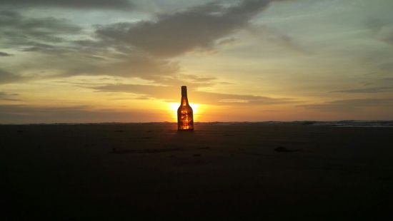 Bei einem Sonnenaufgang stand diese Bierflasche im Sonnenlicht.