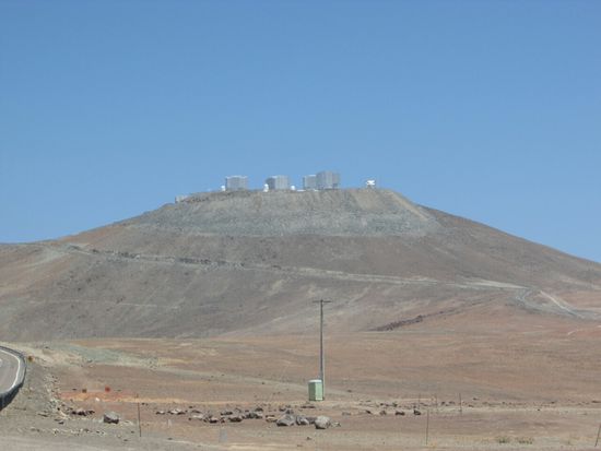 Dort oben in 2.600 m Höhe das Observatorium Paranal.
Das VLT (Very Large Telescope) kombiniert vier Spiegel von je 8,20 m Durchmesser sowie drei kleinere und simuliert so die optische Auflösung eines 200-Meter-Teleskops.