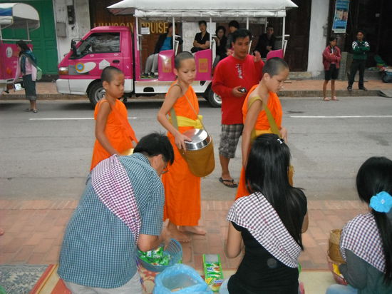 Die Kindermonks vor der franzoesisch laotischen Familie - die karierten Tuecher werden mit den Plaetzen bereitgestellt