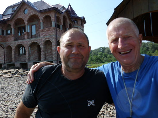 Beim Frühstück an einer Bushaltestelle werde ich angesprochen. Endlich jemand vom Bau!
Er war lange Zeit Bauführer in Portugal bei einer deutschen Baufirma. Sehr gute Bezahlung und 8-Stunden-Tag, aber dann von portugiesischer Firma übernommen, Lohndumping. 
Nein, das hat er nicht mitgemacht und ist in die Ukraine zurückgekehrt. Diese Häuser hier hat er alle gebaut, nur mit Schubkarre ohne Baugerüst, früher hier viele Leute, heute er allein, als Wache. Bis die Bauherren wieder Geld haben.
Er wohne dort hinten, in dem einzigen Haus, wo man Gardinen hinter den Fenstern sieht. Er wünscht mir "allezeit Gute Fahrt" und läßt sich gern mit mir ablichten.