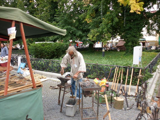 und ein Kunstschmied, der seine Werkstatt mitten auf dem Trödelmarkt aufgeschlagen hat. Er liebt seine Freiheit über alles und liebt sein Handwerk, erst muß ein Werkstück fertig geschmiedet sein, bevor er dem Publikum etwas verkaufen kann.