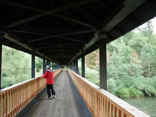 Zunächst bildet die Sauer die Grenze zu Deutschland im deutsch-luxemburgischen Naturpark. Zu Fuß und mit Rad kann man über solche überdachten Brücken beide Seiten erkunden.