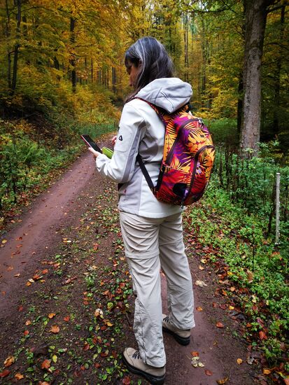 Sabine trägt einen Rucksack, der perfekt den herbstlichen Laubfärbungen angepasst ist 