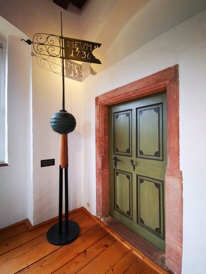 Wetterfahne mit Knauf,  1736, ursprünglich auf dem Dachreiter des Wohnturms bis 1911 eine Neuanfertigung in Kupfer gemacht wurde.