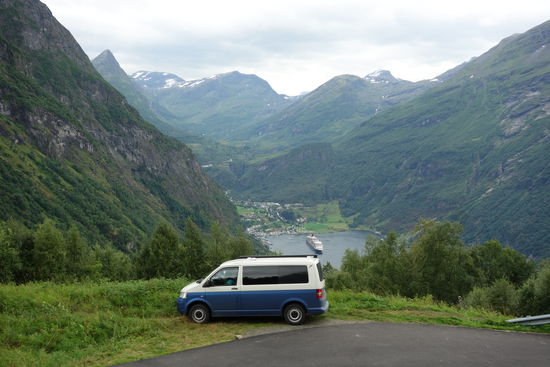 Übernachtung hoch über dem Geirangerfjord mit Blick auf Geiranger und einem Kreuzfahrtschiff.