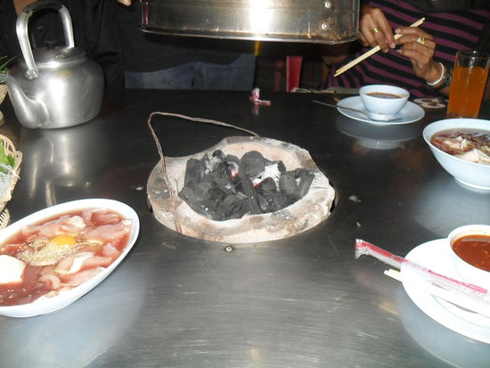 im Tisch war ein Loch und dort wurde dieses Gefäß mit glühender Kohle eingehängt. Links sieht man das noch rohe Fleisch und rohe Ei