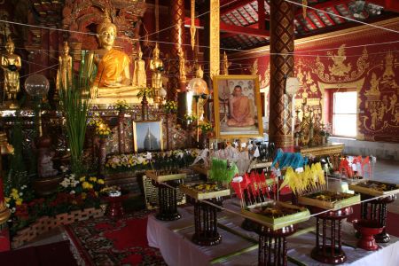 Buddha kniet vor zahlreichen kunstvollen Opfergaben