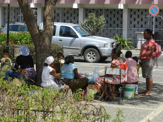 Unter schattigen Bäumen sitzen Frauen, die Bonbons und Zigaretten verkaufen
