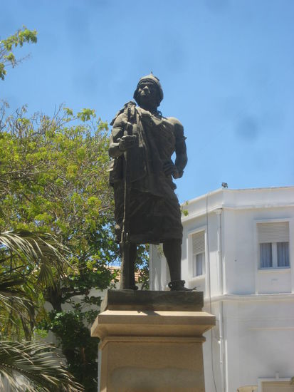 Grimmig schaut der Repräsentant der Ureinwohner Senegals von seinem Sockel vor einem Regierungsgebäude