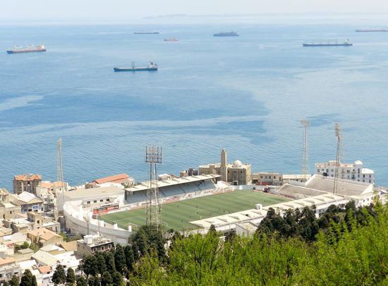Blick von Notre Dame auf das Fußballstadion Algiers und auf Reede liegende Schiffe im Mittelmeer