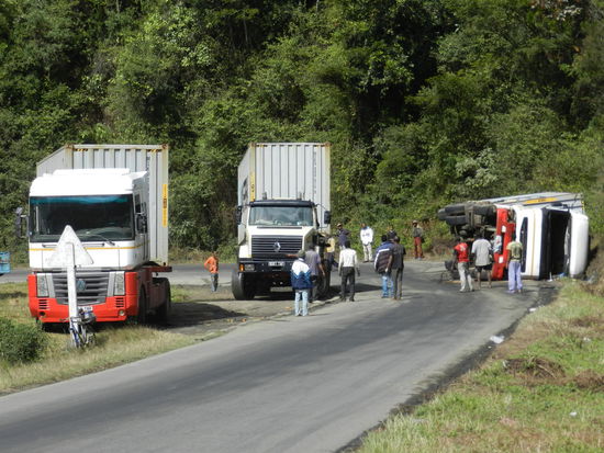 Hier kann der Feuerwehrmann angewandte Mechanik lernen: Von den beiden links stehenden Containern (von vorne: oben rechts gesehen) werden Ketten angeschlagen und vorne und hinten am umgestürzten Container befestigt. Dann fahren beide gleichzeitig los. Dis Straße ist übrigens ungesichert, die Ketten kaum zu sehen...