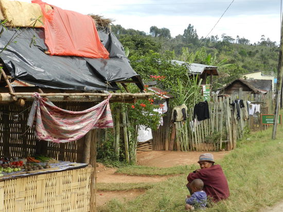 Zur Grace-Lodge läuft man eine Weile auf der Route Nationale 2 entlang. Dort stehen auf beiden Straßenseiten einfache Holzhütten, deren Bewohner sich tagsüber davor aufhalten.