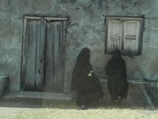 Ganzkörperverschleierte Frauen sitzen vor ihrem Haus