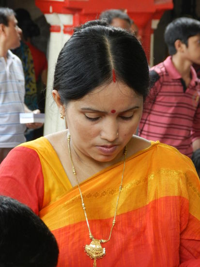Im Gebet am Räucherstäbchentisch versunken; der rote Stirnpunkt ist Zierschmuck, der rote Strich am Haaransatz zeigt an, dass diese Frau verheiratet ist.