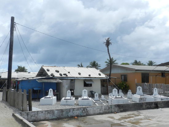 Im Vorgarten spielen Kinder und Hunde zwischen Gräbern