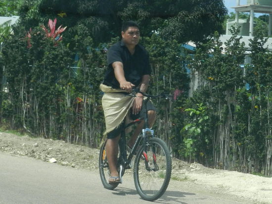 Ab und zu sieht man auch Fahrradfahrer, hier in traditioneller Kleidung mit gewebter Matte
