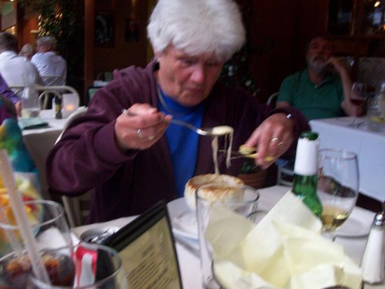 Mutter beim Abendessen. Suppe mit Schere. Sie hat eine französische Zwiebelsuppe gegessen. Die wird mit Schere serviert um den Käse unterhalb des Löffels abschneiden zu können.