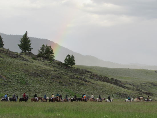 Regenbogen über den abziehenden Reitern in der Prärie