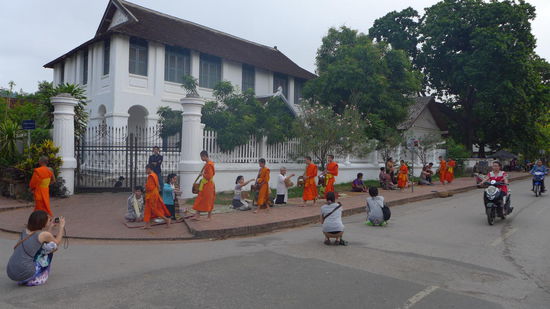 Die "Alms Ceremony" hat nichts mit einer Bergbauerntradition zu tun. Eher mit einer "Allmosen Zeremonie". Die Moenche aller Tempel ringsum sind morgens zwischen 5 und 6 Uhr in der Stadt unterwegs, um Gaben einzusammeln. Das ist eigentlich eine sehr heilige Prozession. Da die orangenen Moenche jedoch auch ein gutes Fotomotiv abgeben, verkommt das ganze zu einer Touristenattraktion. Ich selber habe auch nur zaghaft und aus etwas Entfernung dieses Foto gemacht.