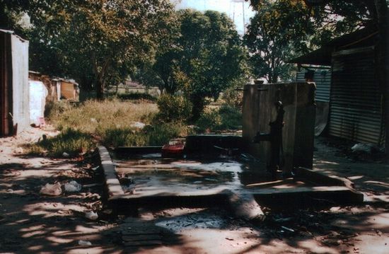 Öffentliche Wasserstelle am Dorf. Innerhalb der Einfassung wird sich meist morgens gewaschen, für die Wäsche kommen die Frauen unter Tags. Die Anzahl solcher Brunnen auf Gemeindekosten hat aufgrund staatlicher Förderung stark zugenommen.
Kanaldeckel sind in Indien meist aus Beton, da die eisernen für ihren Metallgehalt gestohlen werden.