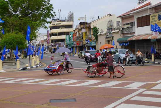 Beliebtes Fortbewegungsmittel: Trishaw. Im Hintergrund die blauen Wahlflaggen