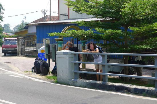 Warten auf den Bus, der irgendwann kommen soll. Zum Glück ist die "Haltestelle" schattig.