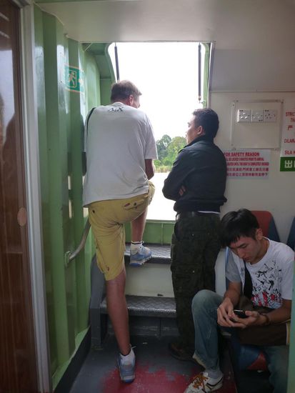 Man trifft sich zum Aufwärmen im Einstiegsbereich des Bootes. Oliver im Gespräch mit dem jungen Mann vom Volk der Iban