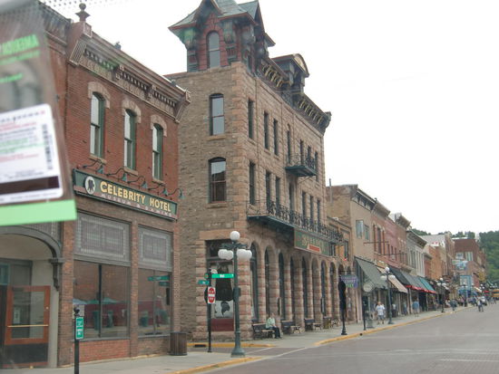 Gregor erzählte mir von der Westernstadt Deadwood. Schade - heute am Montag wird die Erschießung eines 'soundso' nicht gespielt. Aber wir können uns ja so die Stadt ansehen.
Dann hatte Gregor doch keine Lust die Stadt anzusehen.
Wenn Du willst dann halte ich und gehe mit!
Du bist doch gerade dabei aus der Stadt raus zu fahren!
Ich drehe wieder um wenn Du willst!
Ich weiß aber noch nicht genau ob ich hier aussteigen will!
Nachher habe ich mich wieder geärgert doch nicht gehalten zu haben um mir die Stadt anzusehen auch wenn es nur Souvenirshops und Spielhallen gibt.  Sie sah jedenfalls ganz lustig aus und viele Besucher kamen als Cowboys. Obwohl hier - in Wyoming - es schon viele Amis gibt die ganz normal in Jeans und Cowboyhut unterwegs sind!