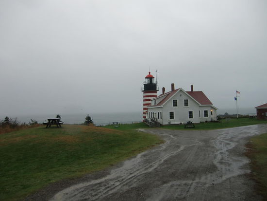 Dann fing es auch noch an in Strömen zu regnen!
Ich wollte doch zu gerne mal den Quoddy Leuchtturm sehen!
Der hat so ein schönes Ringelsocken-Muster!!!
Der gehörte mit zu einem State Park und als wir hier ausstiegen war erst einmal auf dem Parkplatz 'Camping verboten' und dann hing eine Metallbox dort mit einem Schild das den Besucher aufforderte für die Besichtigung des Leuchtturms 3 $ p.P. zu bezahlen.
Gregor blieb im Regen dort stehen während ich - ohne zu bezahlen - weiter ging um mal einen kurzen Blick auf die Anlage zu werfen.
Nichts zu sehen - Nebel! 
Dafür hatten wir beide klatschnasse Hosenbeine!
Nach einem Cappuccino im Auto entschlossen wir uns zur Weiterfahrt da sich Gregor hier so einsam nicht wohl fühlte.
Was danach kam,  war wie immer das Gleiche! Landstrasse, rechts und links Häuser, keine Parkplätze, kein Ort.
Fast dunkel entdeckten wir ein Schild 'Viewpoint 1000 feet'!
Eine Ausbuchtung an der Strasse. Dort übernachteten wir sogar sehr ruhig. Es fuhr abends kein Auto mehr hier entlang!
Am nächsten Morgen rätselte ich allerdings darüber nach was es hier zu sehen gibt!? Wasser und ein kurzes Stück Uferlinie mit einem Haus am Ende!