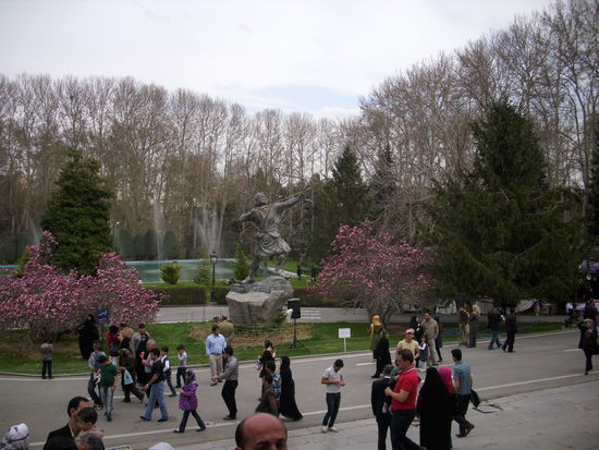 Parkszene vor dem Weißen Shah-Palast mit Magnolien und Heldenstandbild.