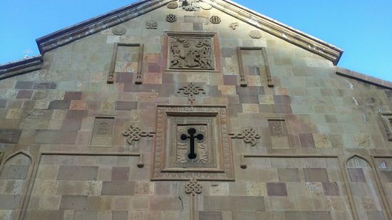 Die Außenfassade der Kirche mit den typischen armenischen Flachreliefs und Kreuzsteinen.