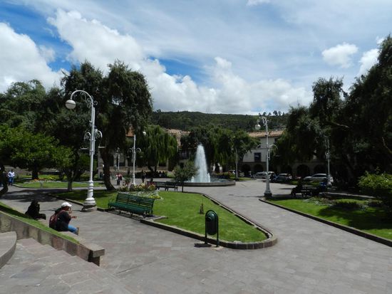 Ein kleiner Platz mit einem Springbrunnen. Überall sind Bänke aufgestellt und die Menschen sitzen dort und relaxen, auch an der Kathedrale ist es so.