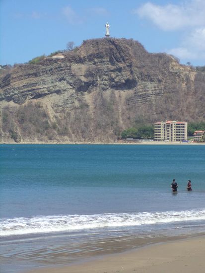 Am Strand angekommen, genießen wir von einem Restaurant den Blick auf das Meer und den Hügel mit einer Christusfigur.