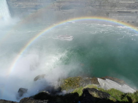 Unten können wir ein Schiff sehen, das ganz nahe an die Stelle fährt, wo das Wasser herunterfällt. Alle Passagiere sind in rote Anzüge verpackt, damit sie nicht total naß werden und, wenn das Boot mal kentert, man sie besser im Wasser sieht 