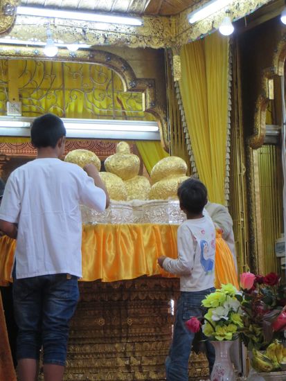 Neben den Blumen wurden auch Buddhafiguren mit kleinen Blattgoldplättchen beklebt. Die Figur sieht schon ganz unförmig aus.
