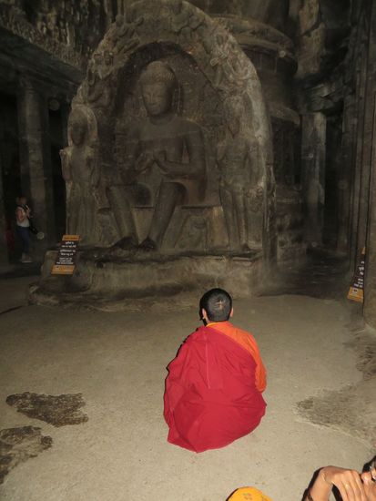 Der Mönch sitzt versunken vor dem Buddhabild und  meditiert
