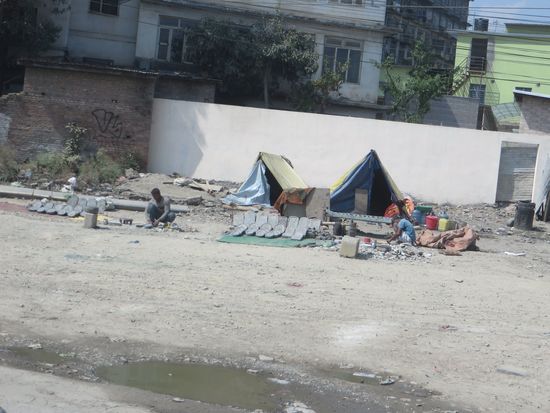 Handwerker sitzen hier auf der Straße und arbeiten, sie schlafen in den Zelten.